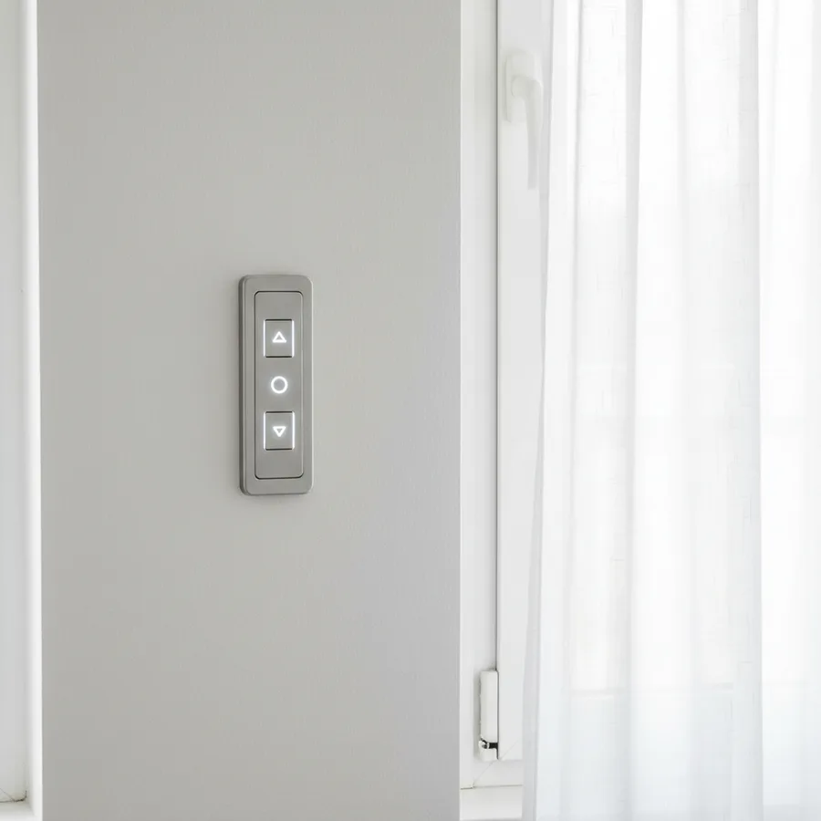 Pulsador de pared para persiana eléctrica instalado junto a una ventana